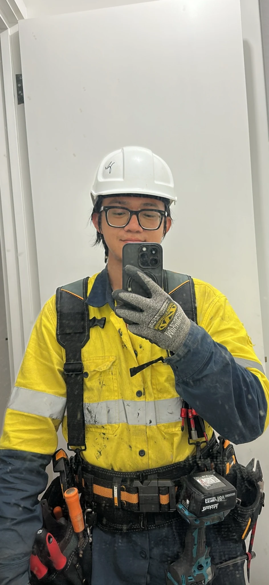 Haomin Yang on a construction site wearing high-visibility workwear and a hard hat